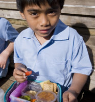 Child eating food out of lunch box at school